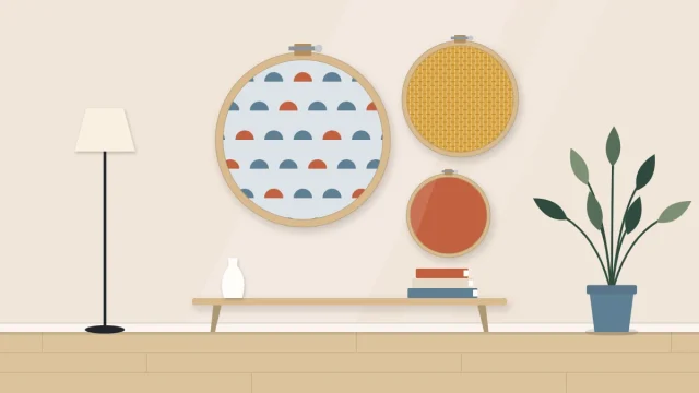 Three embroidery hoops of different sizes clustered on a wall, holding a patterned, a plain-weave and a solid fabric