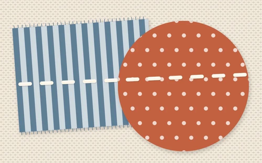 Close view of two overlapping fabric shapes with a row of short running stitches crossing both