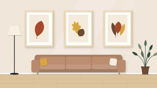 A row of three identical frames on a wall holding a matching set of simple pieces with leaf shapes in warm colors