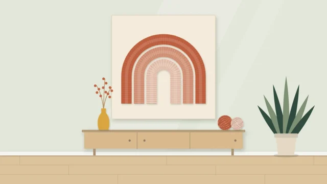 Three nested yarn-wrapped arches in graduated colors mounted on a pale board on a wall